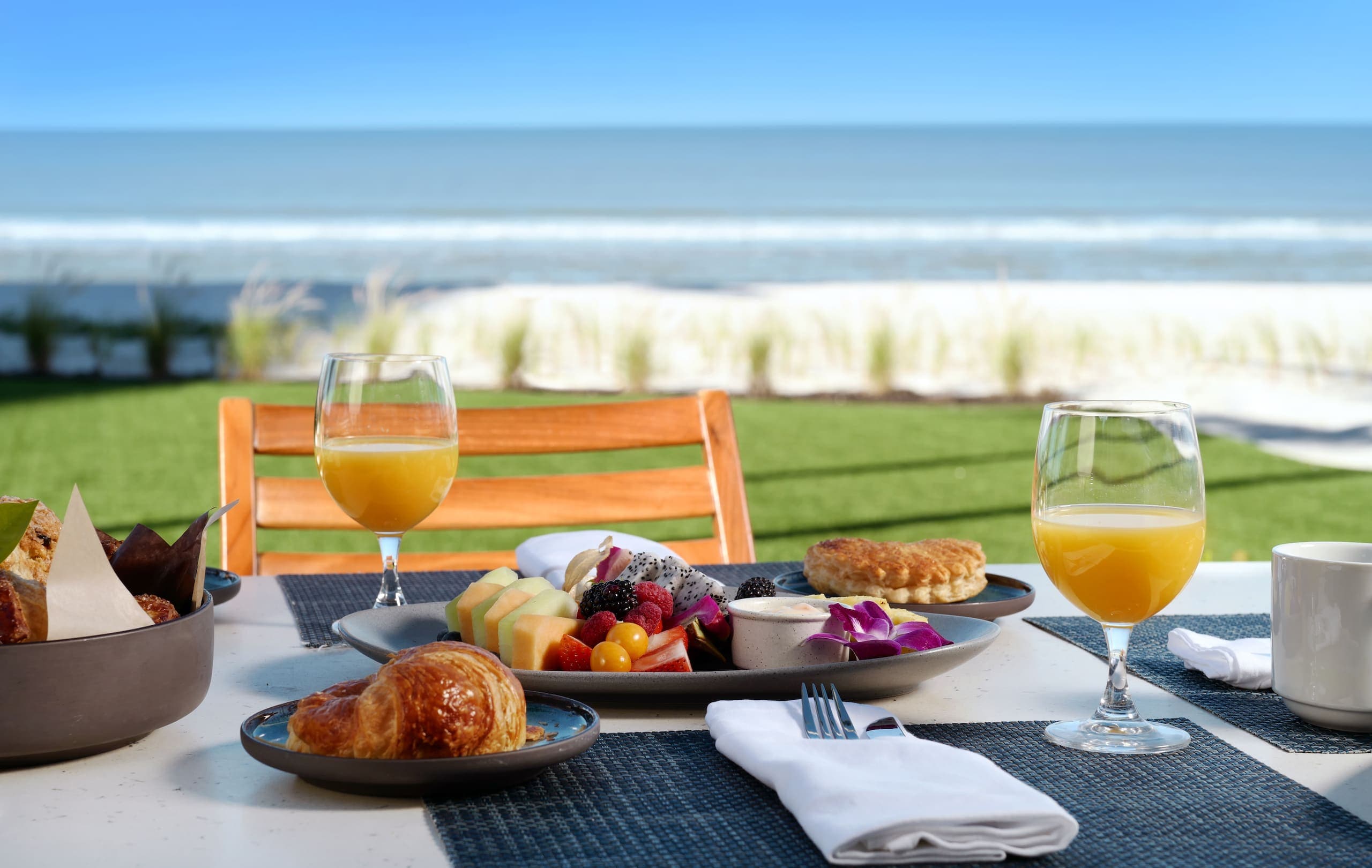 A breakfast spread of food with orange juice, mixed fruits and croissants