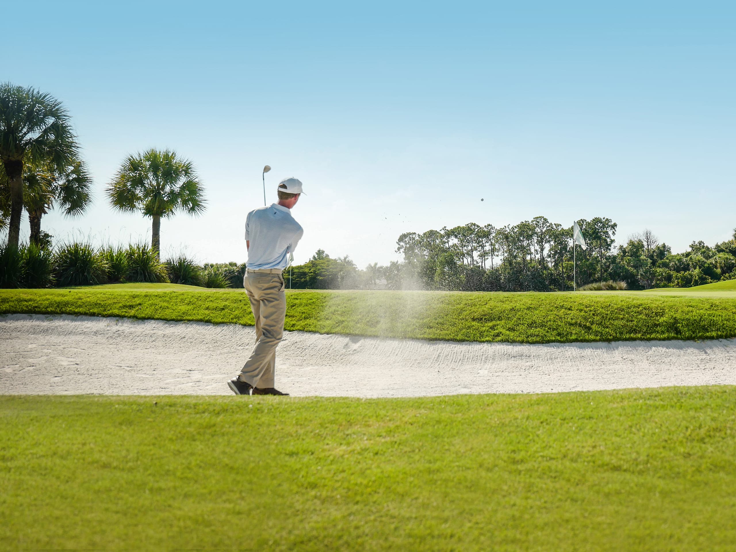 A man golfing from the sand trap on the golf course