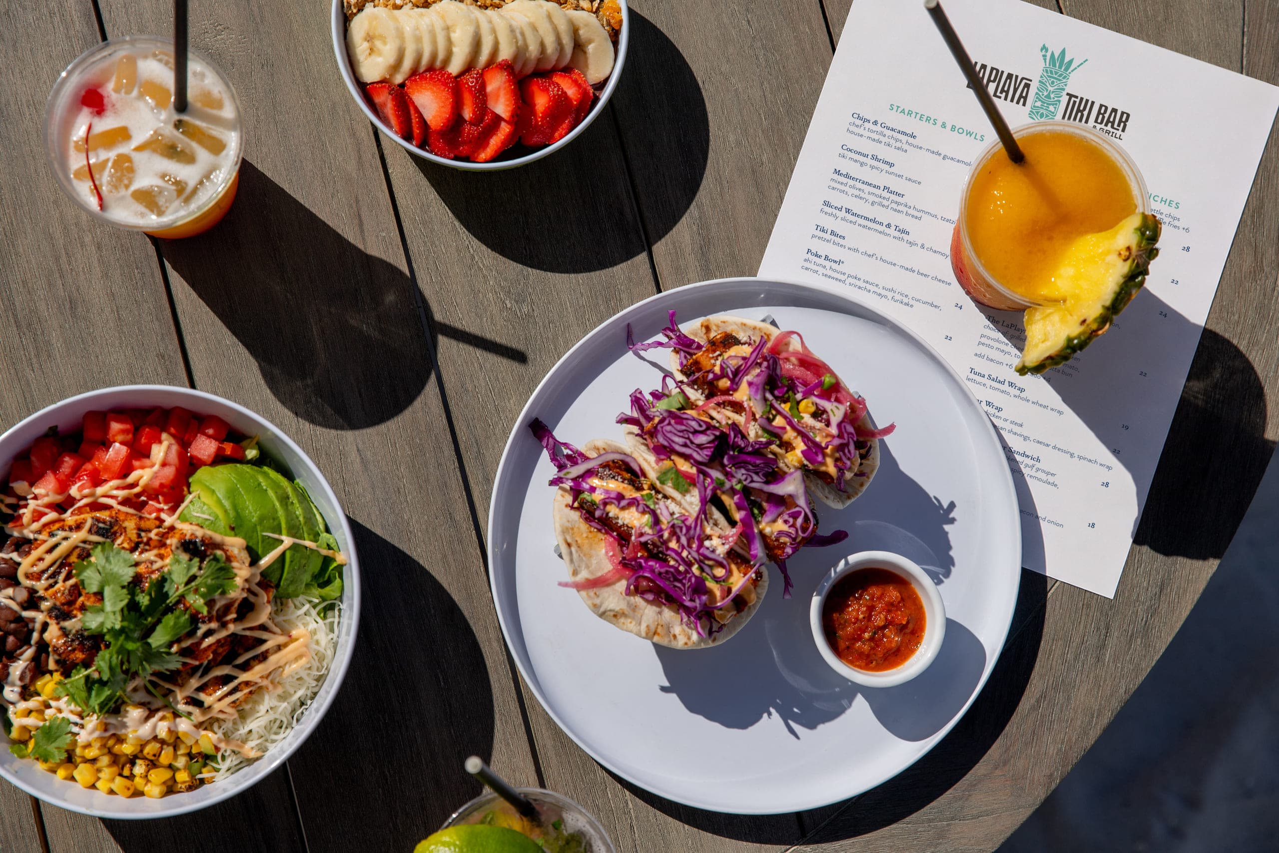 A spread of food and drinks on a table at the Poolside Tiki Bar