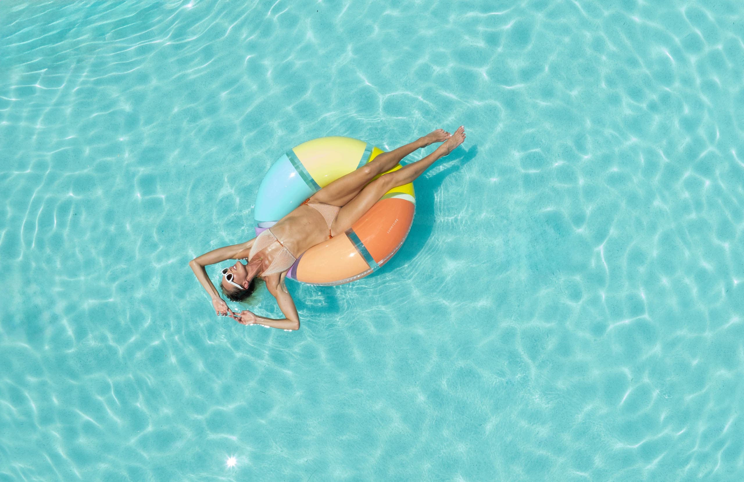 a woman lounging in a pool on an inflatable donut