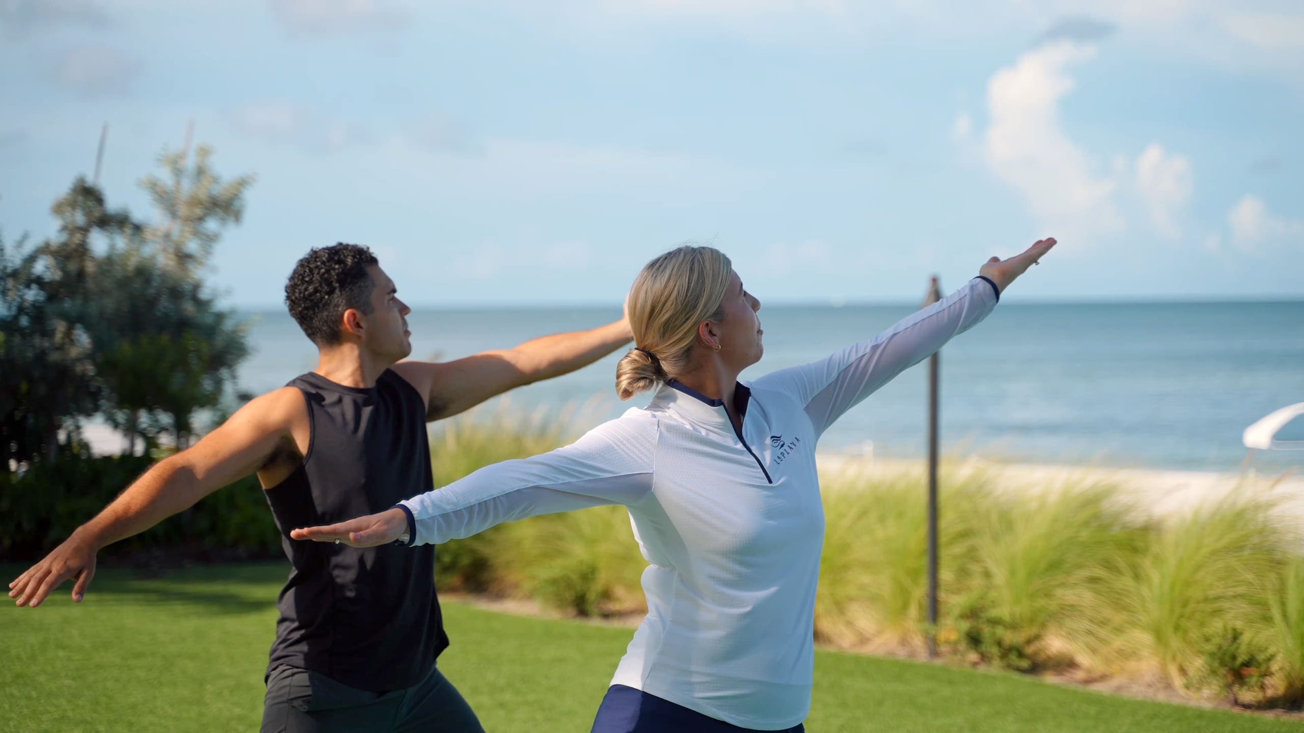 A man and woman doing yoga on the lawn