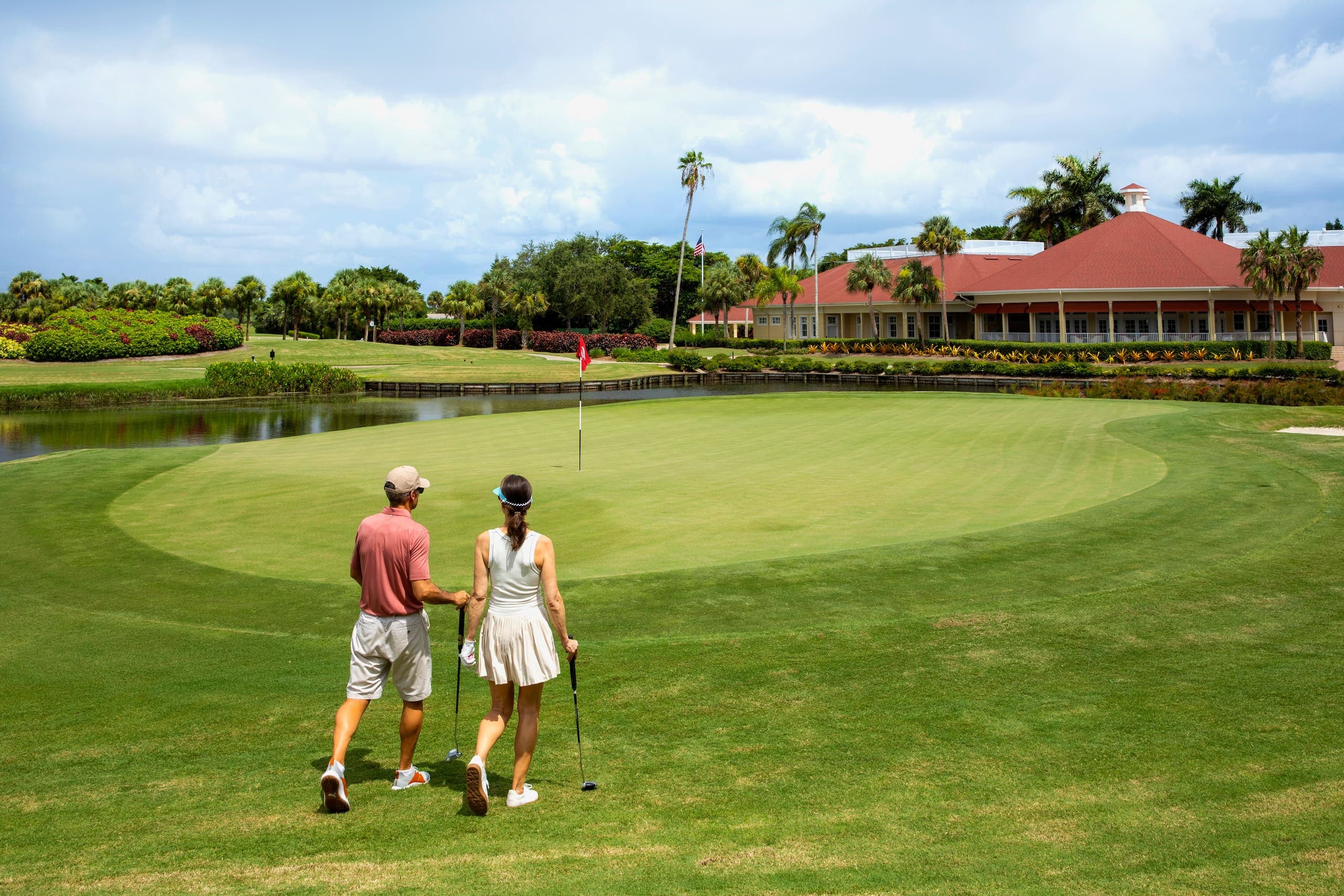 Two people waling towards a green on the golf course