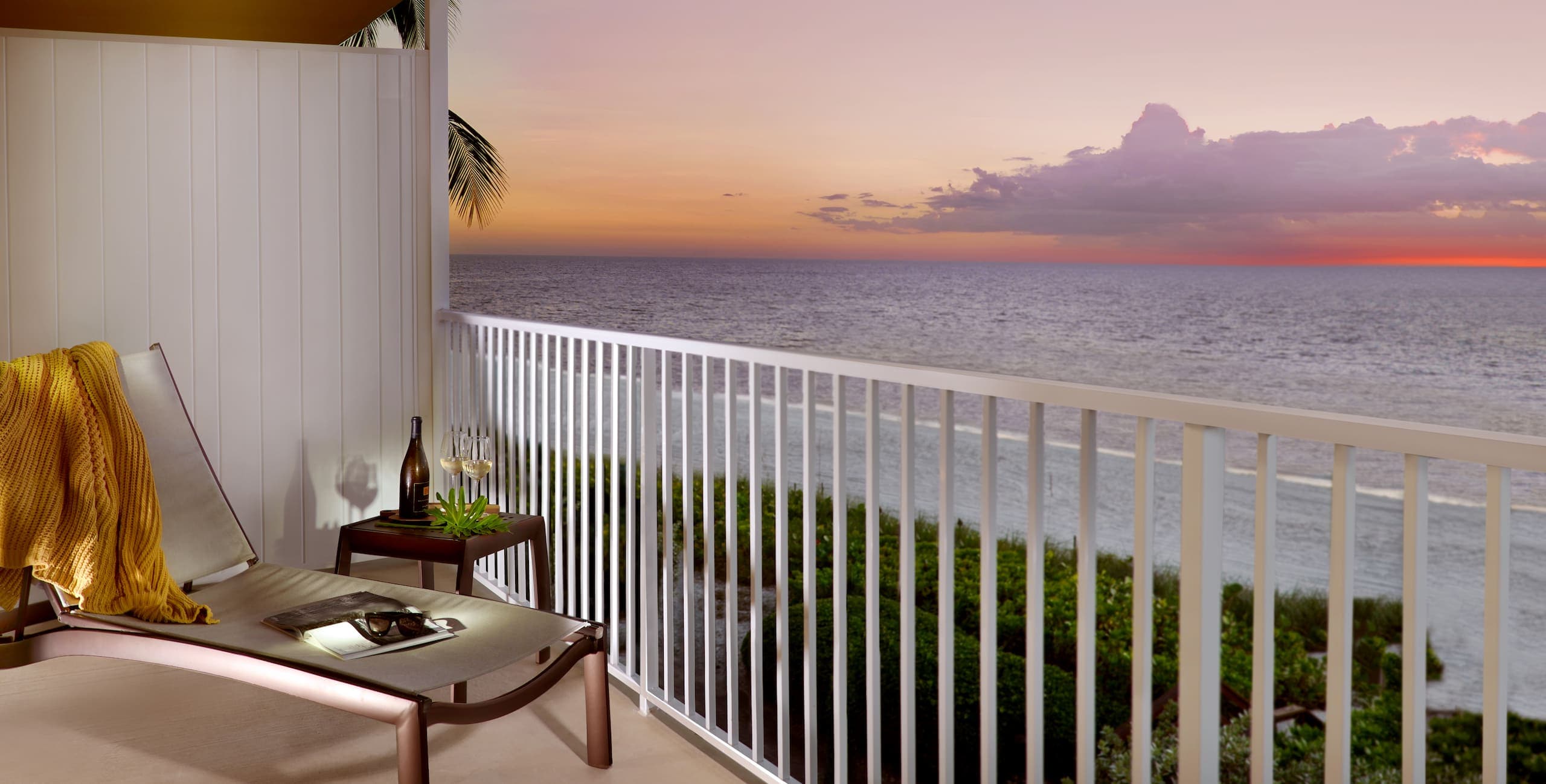 A view of the sunset over the water on the balcony in a Laplaya Beach Front Beach House Room