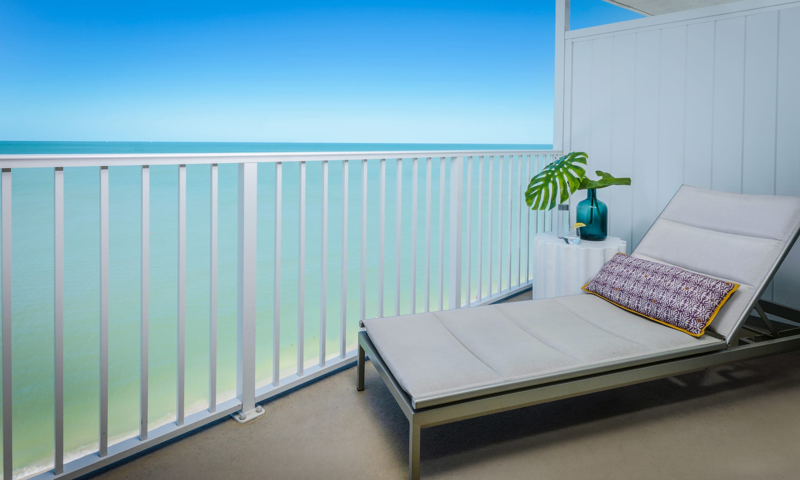 The balcony with a lounge chair over looking the water in a Laplaya Beach Front King room
