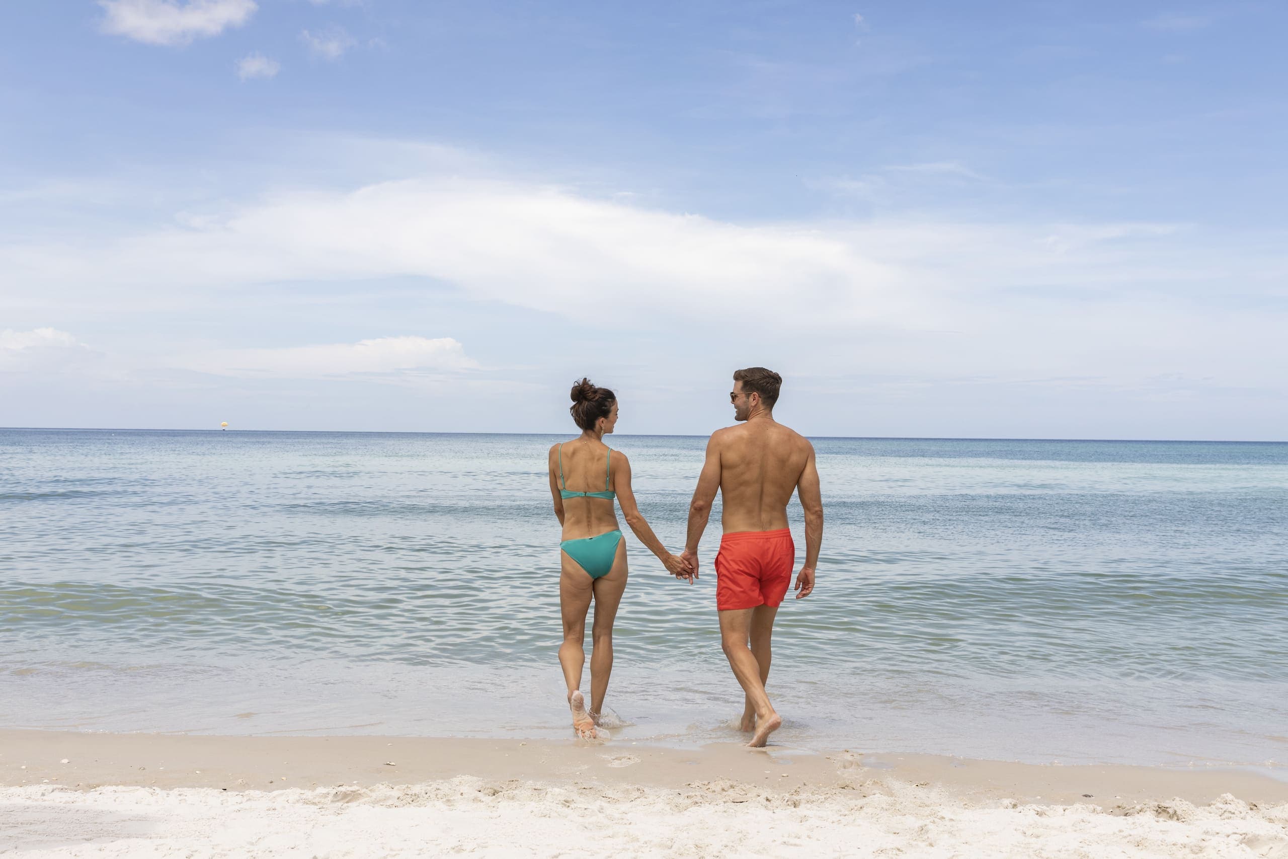 A couple walking into the water on the beach at LaPlaya