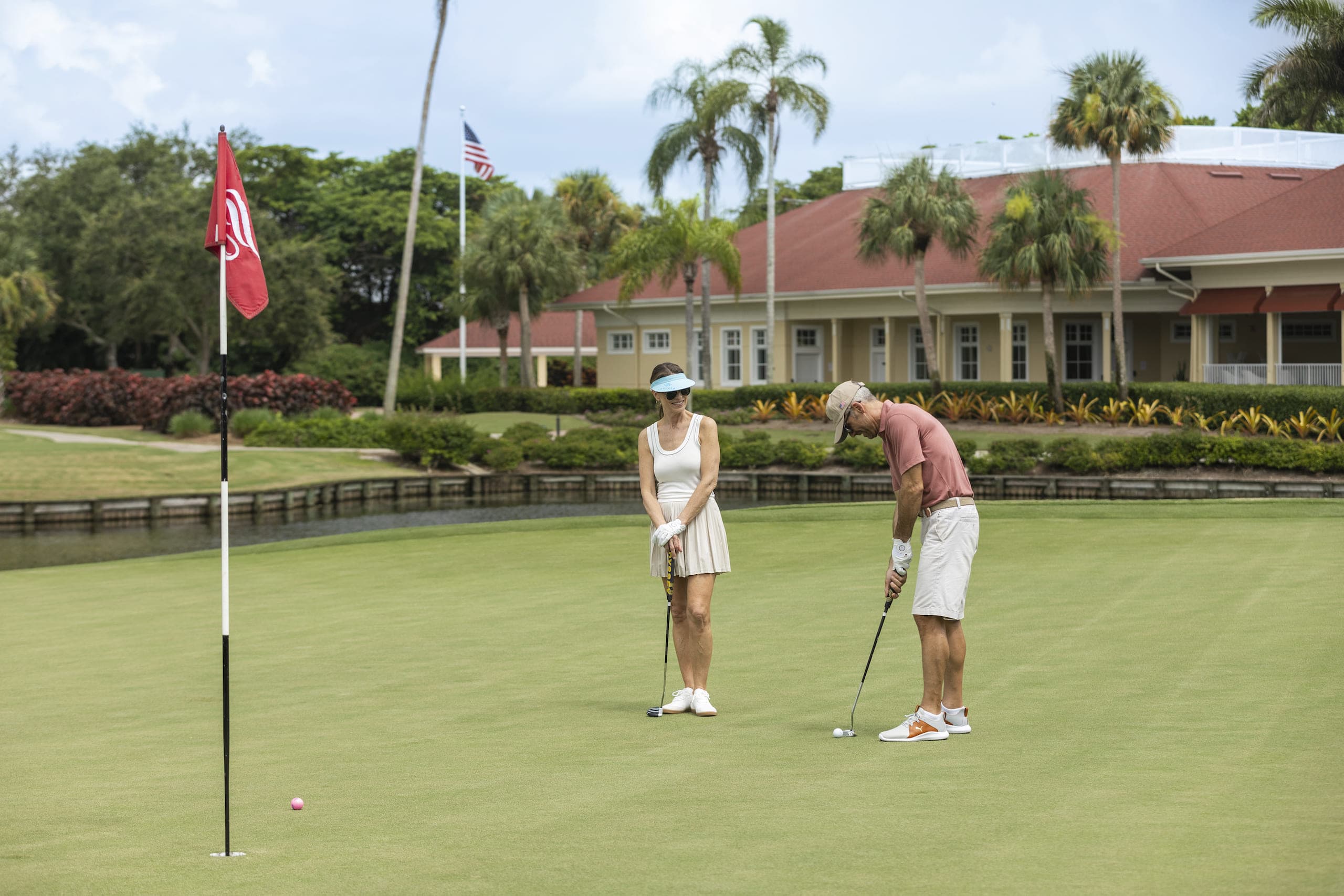 A man putting on the green with a woman watching
