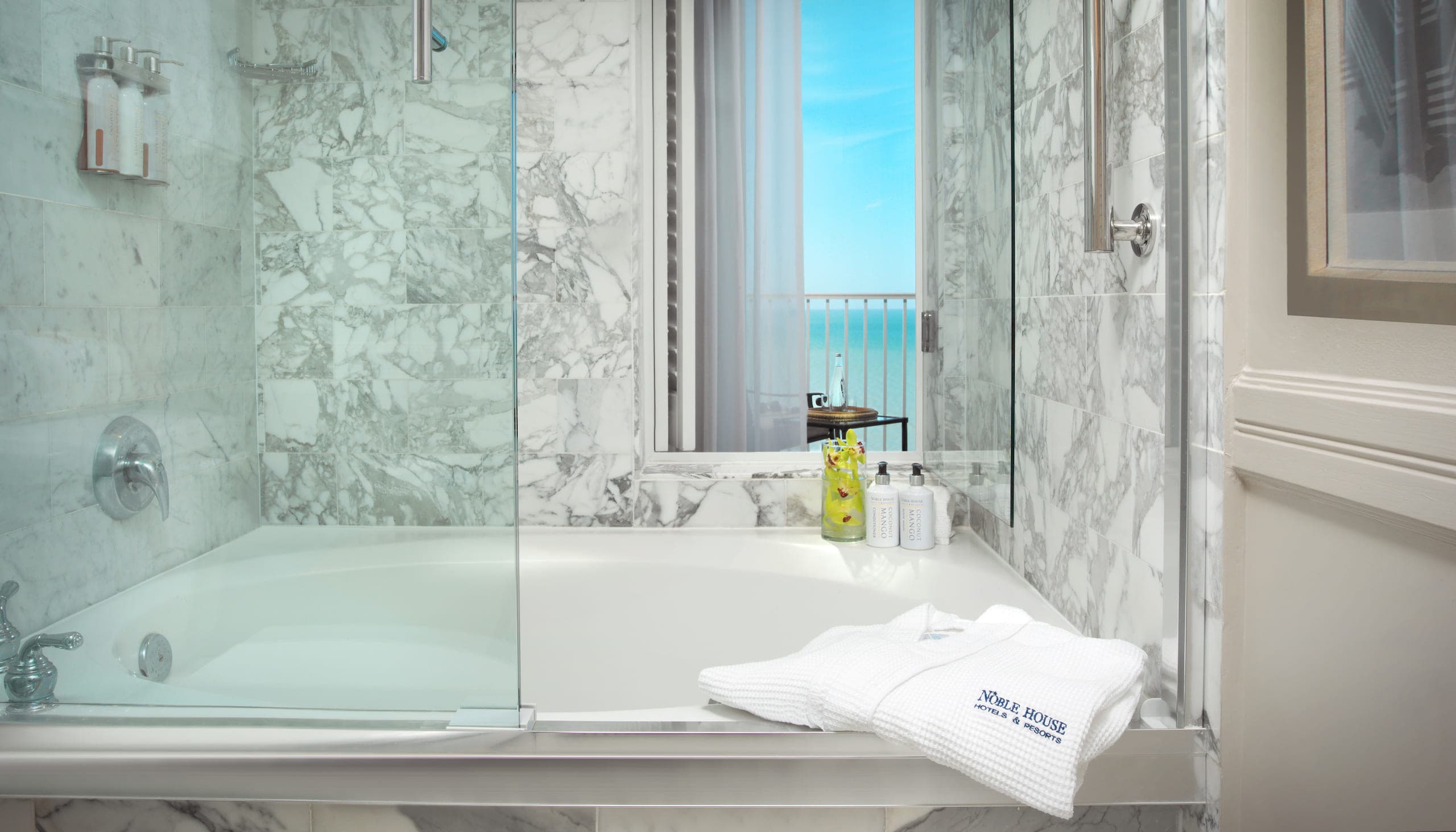 A tub with a window leading to the balcony with a view of the water in a Laplaya Gulf Tower King Suite