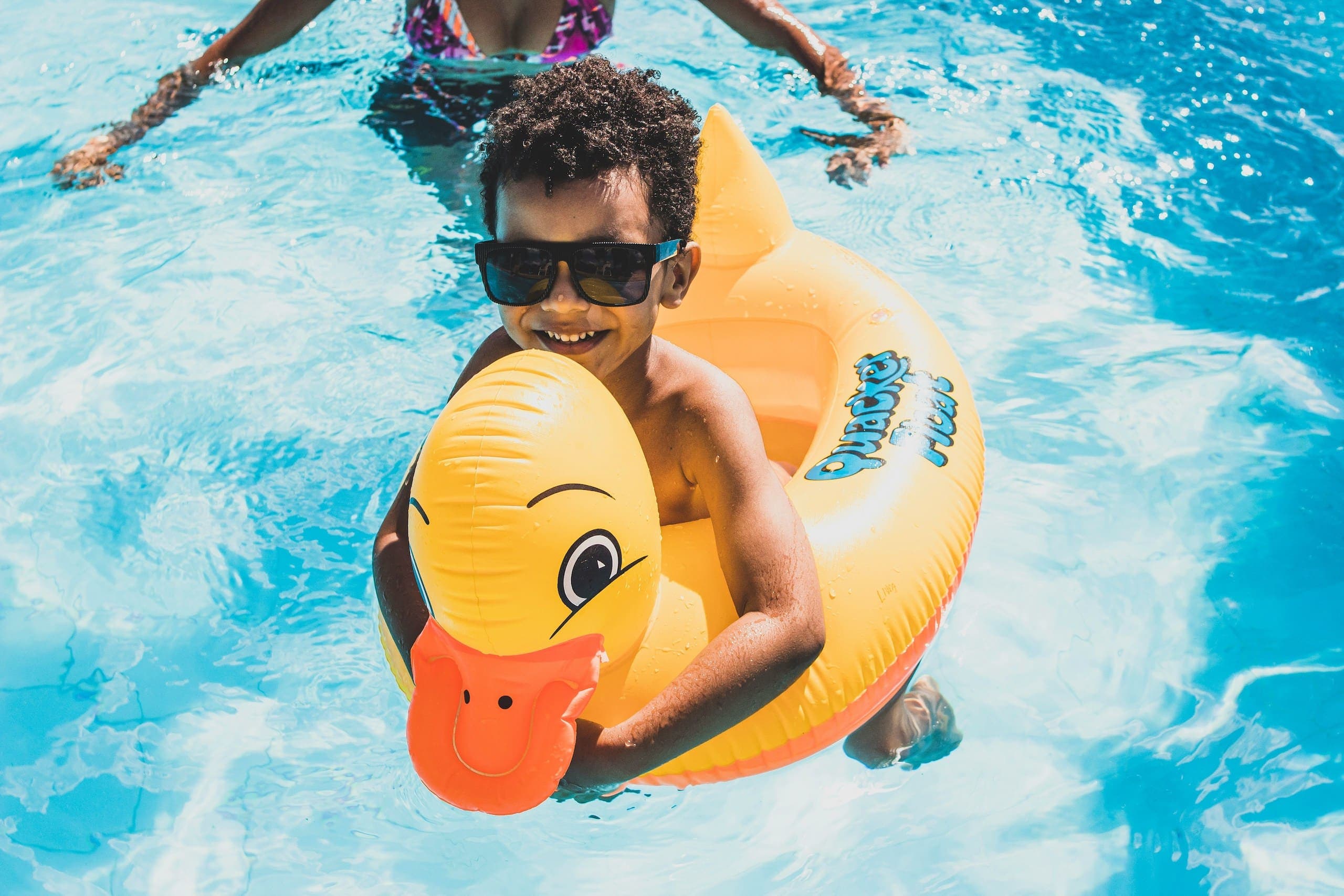 A child having fun in the pool with a duck floaty