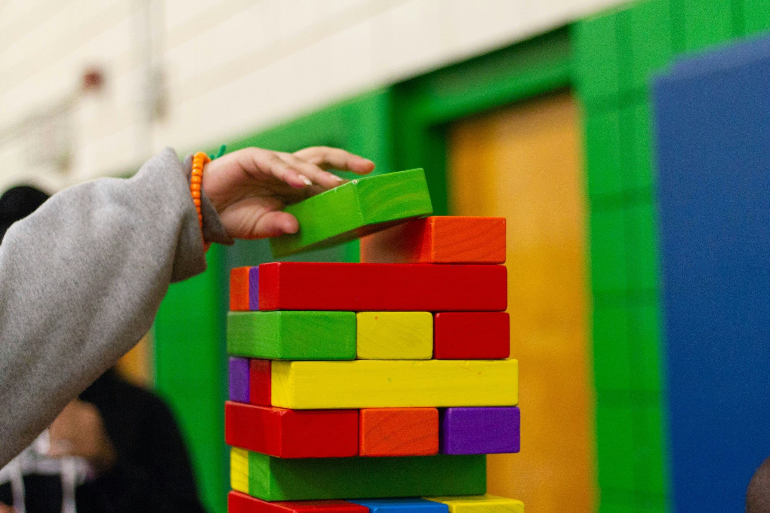A child adding a colored Jenga block