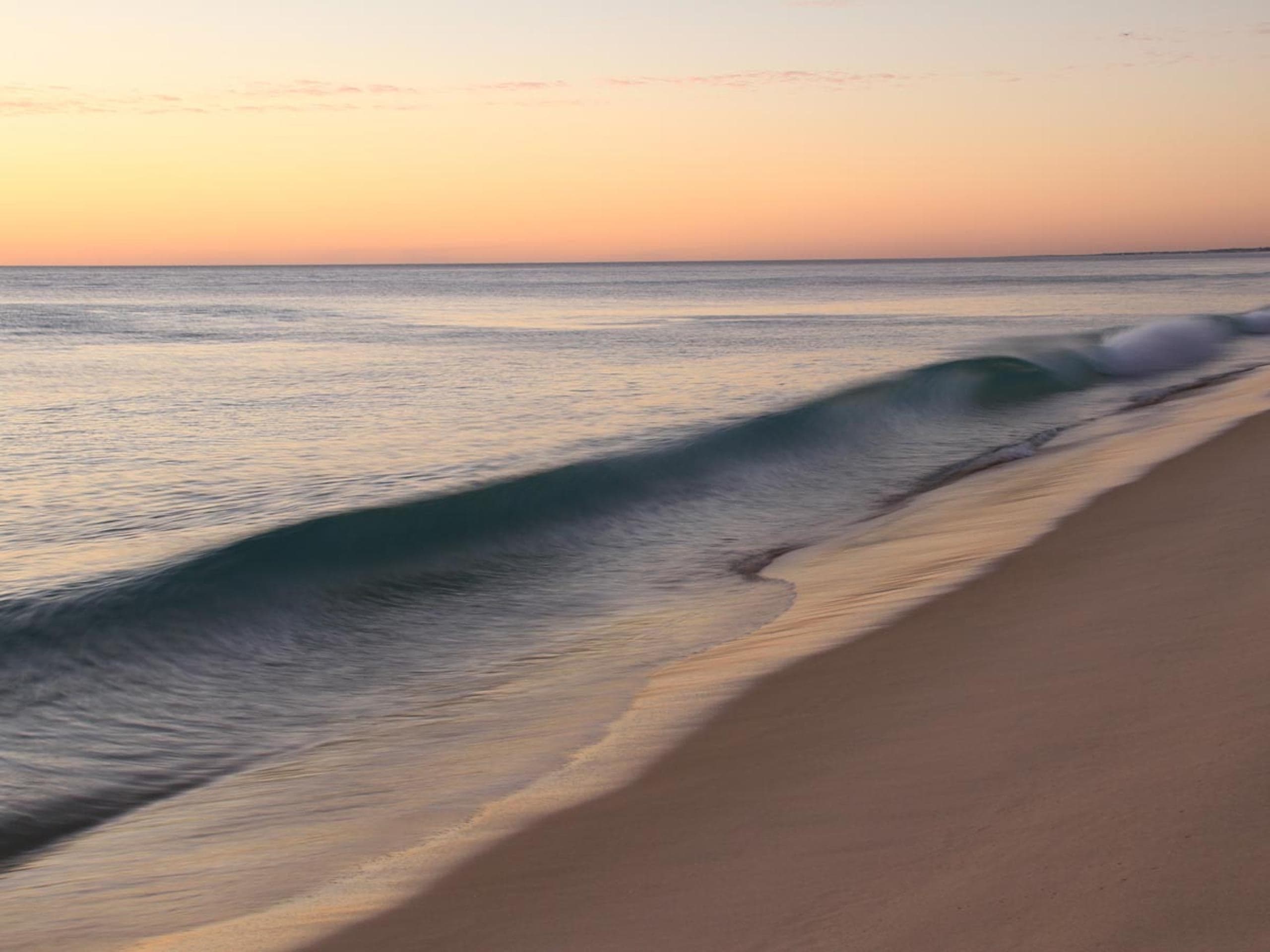 Smooth waves crashing the shore at sunset