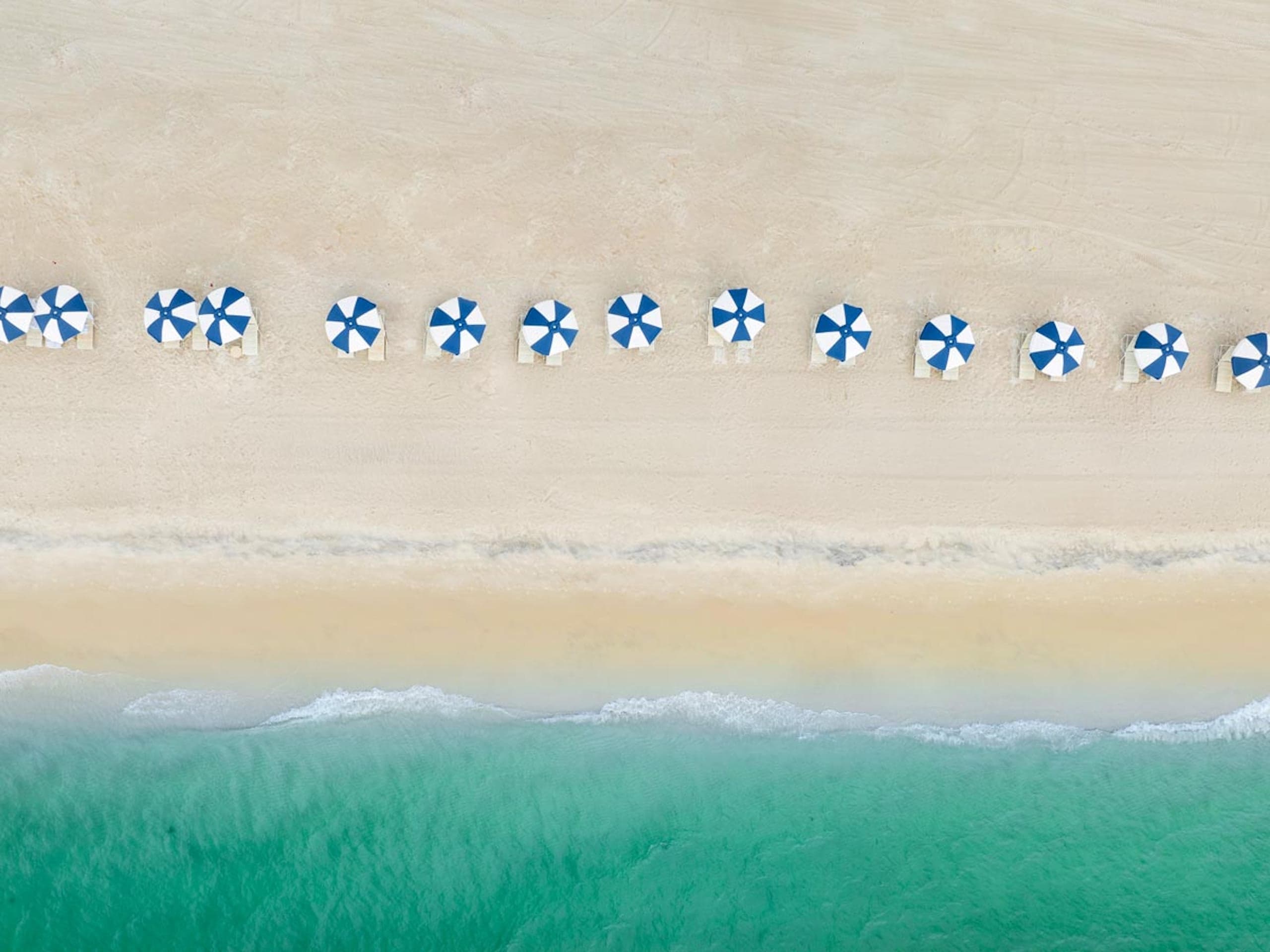 Aerial view of the LaPlaya beach with 14 umbrella lines up along the beach