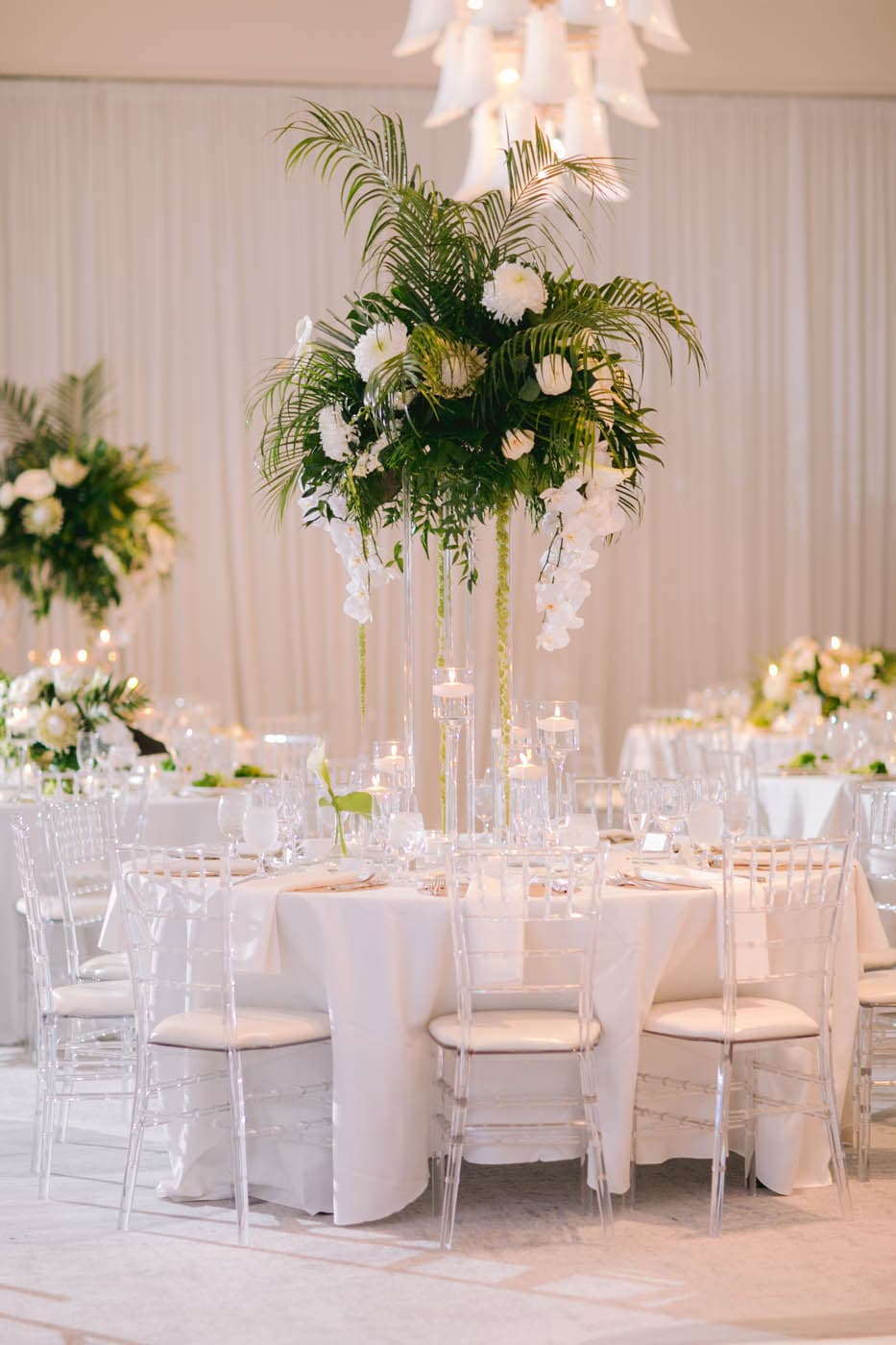 A table with white table cloth and clear chairs in a venue at LaPlaya