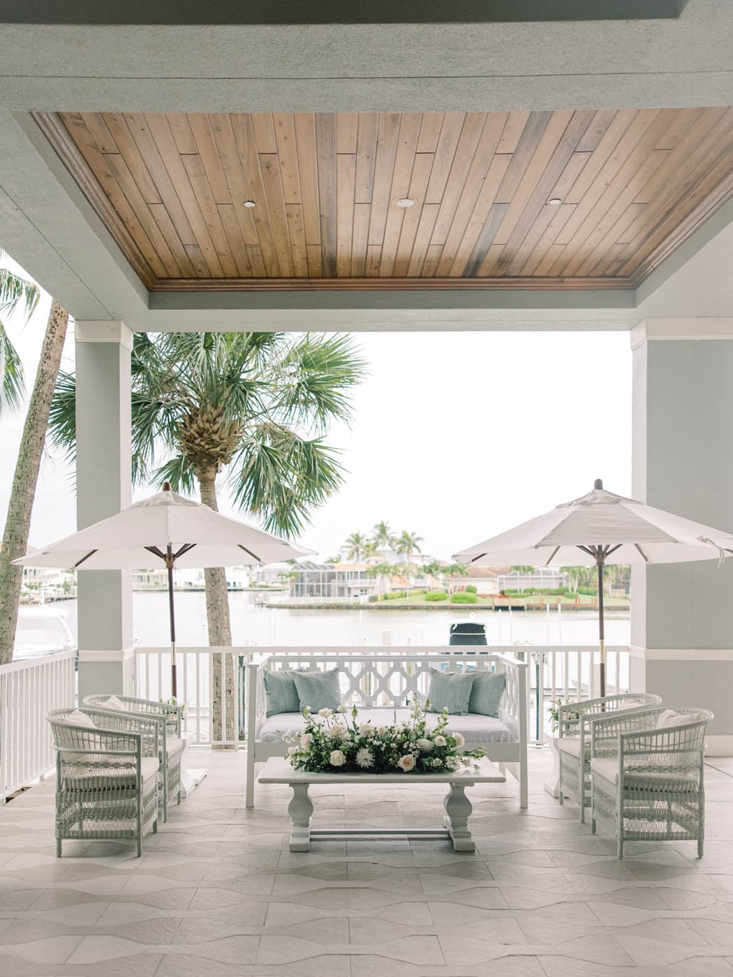 A patio beside the water with some patio furniture and 2 umbrellas at LaPlaya