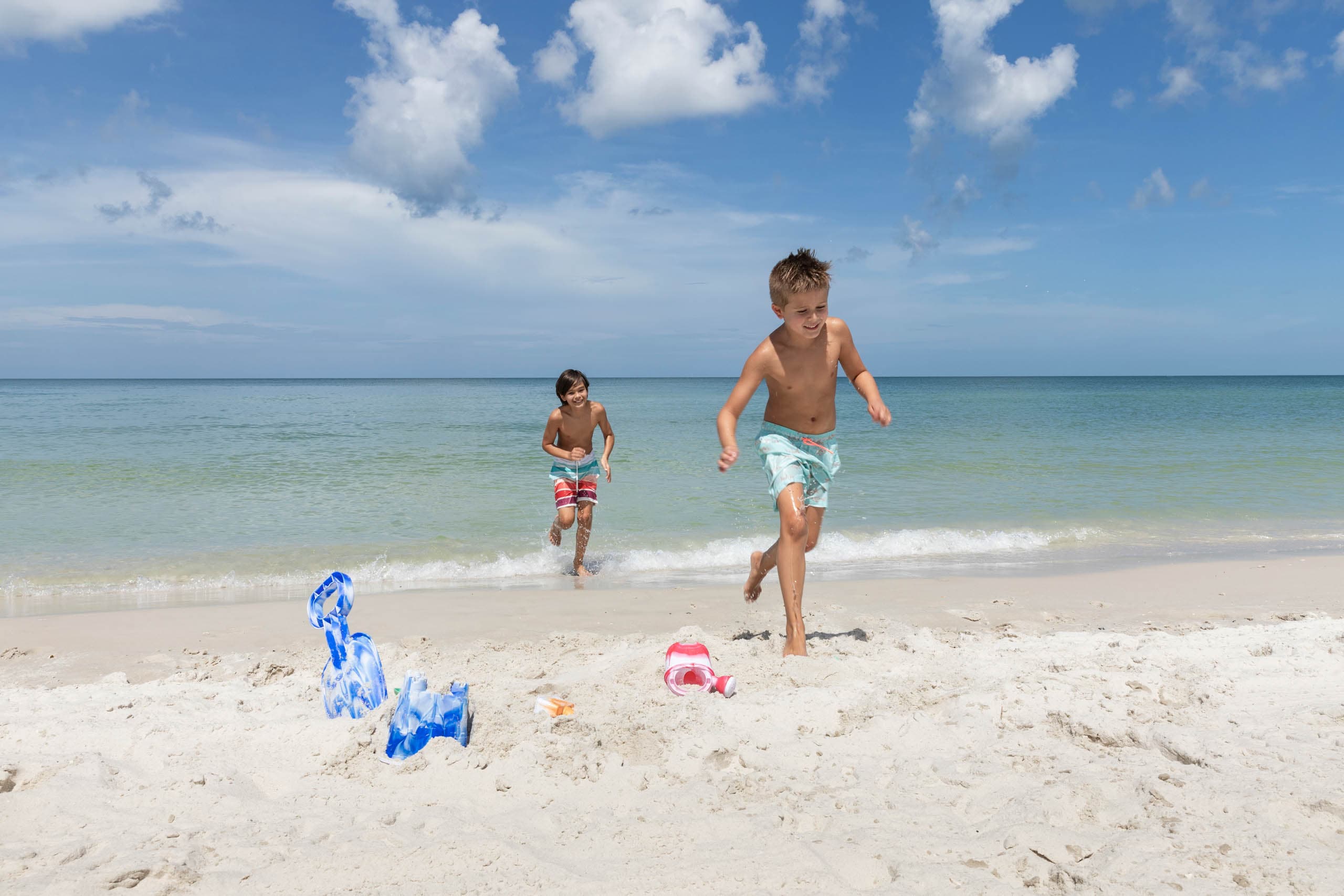 two young boys running on a sunny beach