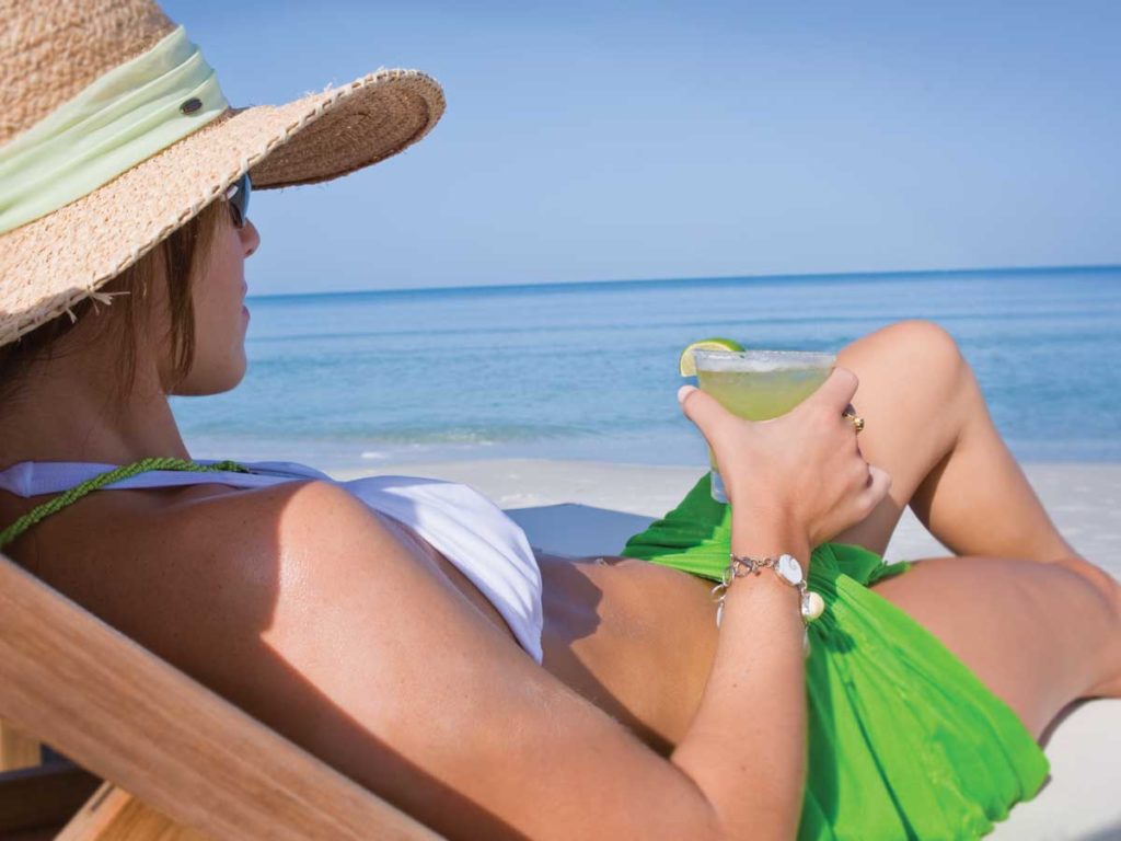 Woman on beach with cocktail in Naples, Florida