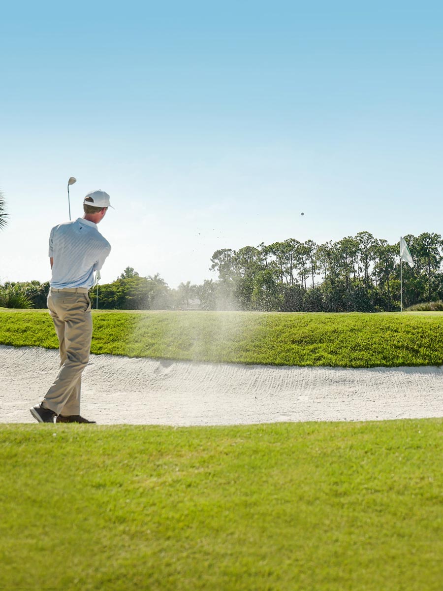 Golfer hitting ball from sand trap in La Playa Beach and Golf Resort