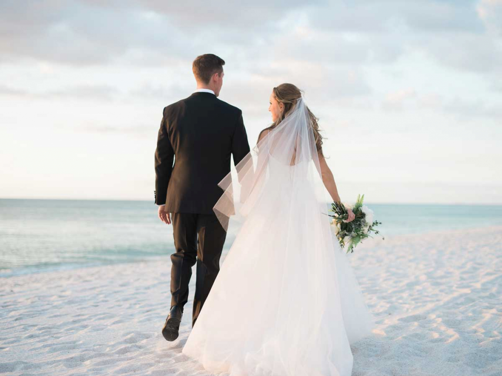 Newly weds holding hands on beach in Naples, Florida