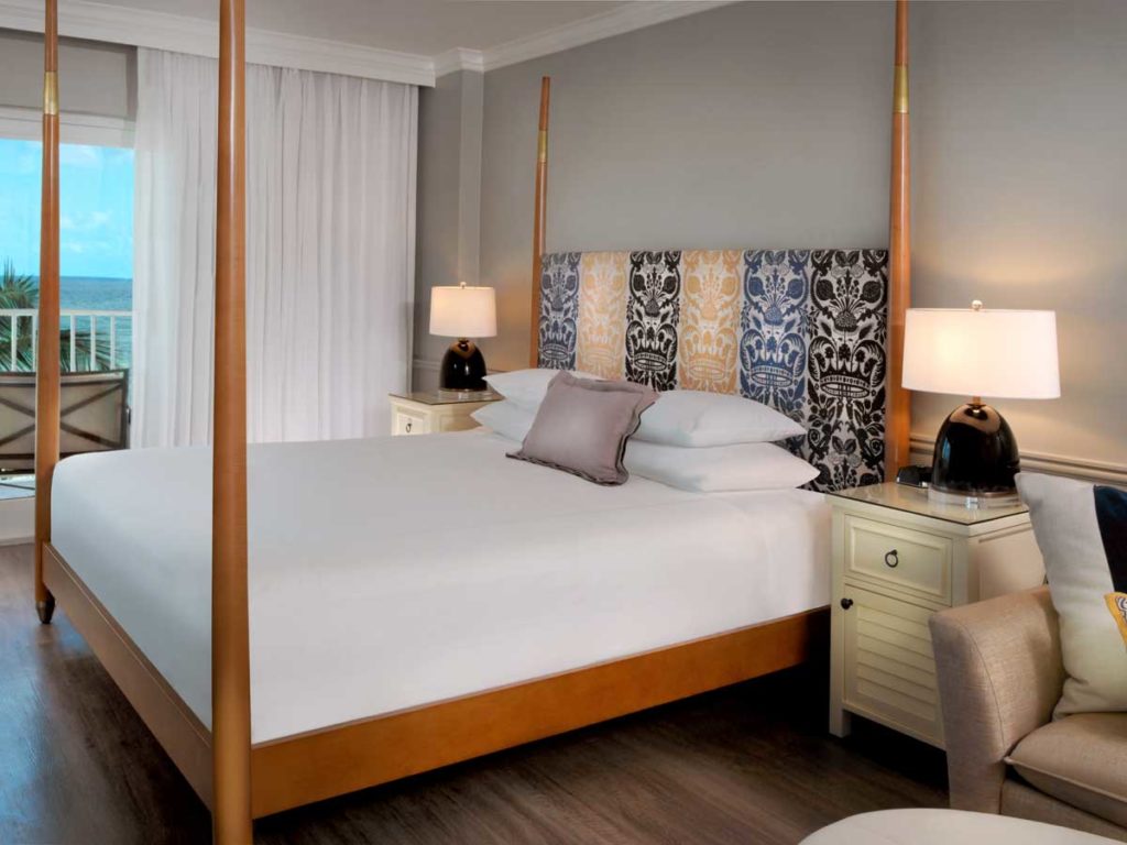 King sized bed guestroom with balcony and water views in Naples, FL