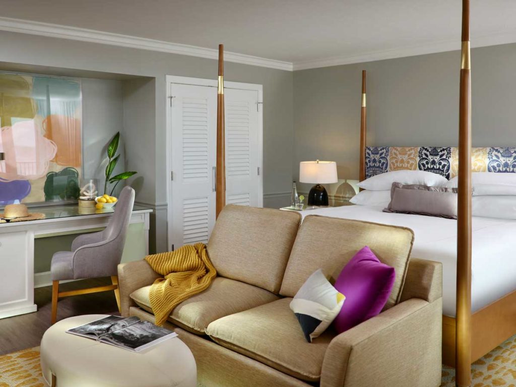 Guestroom with king sized bed, sitting area, and desk in Naples, FL