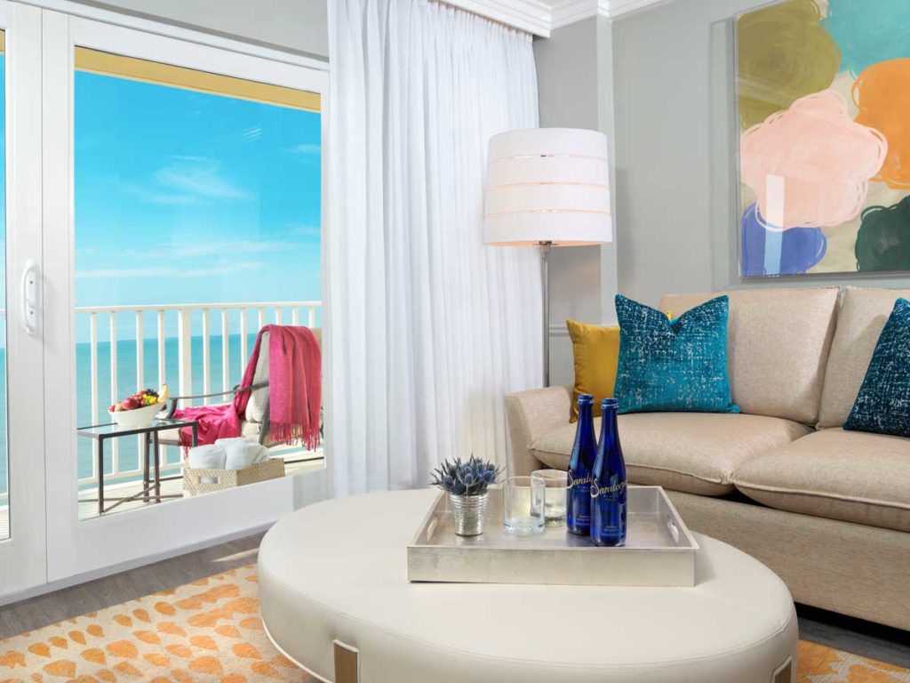 Hotel suite in Naples, FL with sitting are and balcony with water view.
