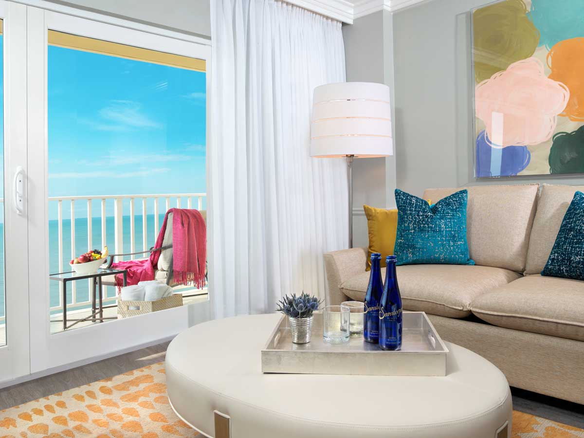 Hotel suite in Naples, FL with sitting are and balcony with water view.