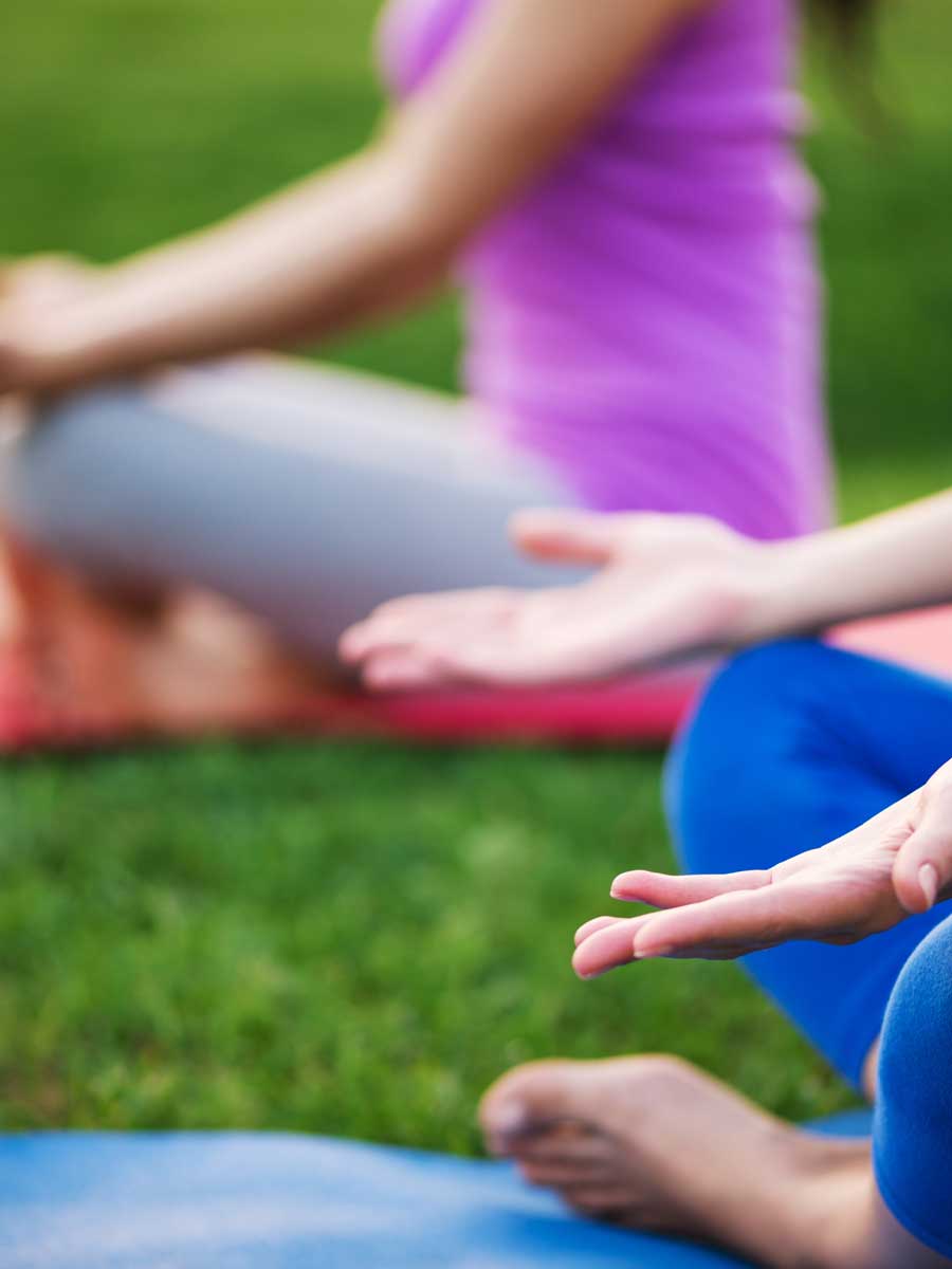 two women doing yoga on grass