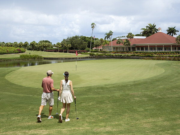 Couple walking toward putting green near clubhouse at LaPlaya Beach & Golf Resort in Naples, FL